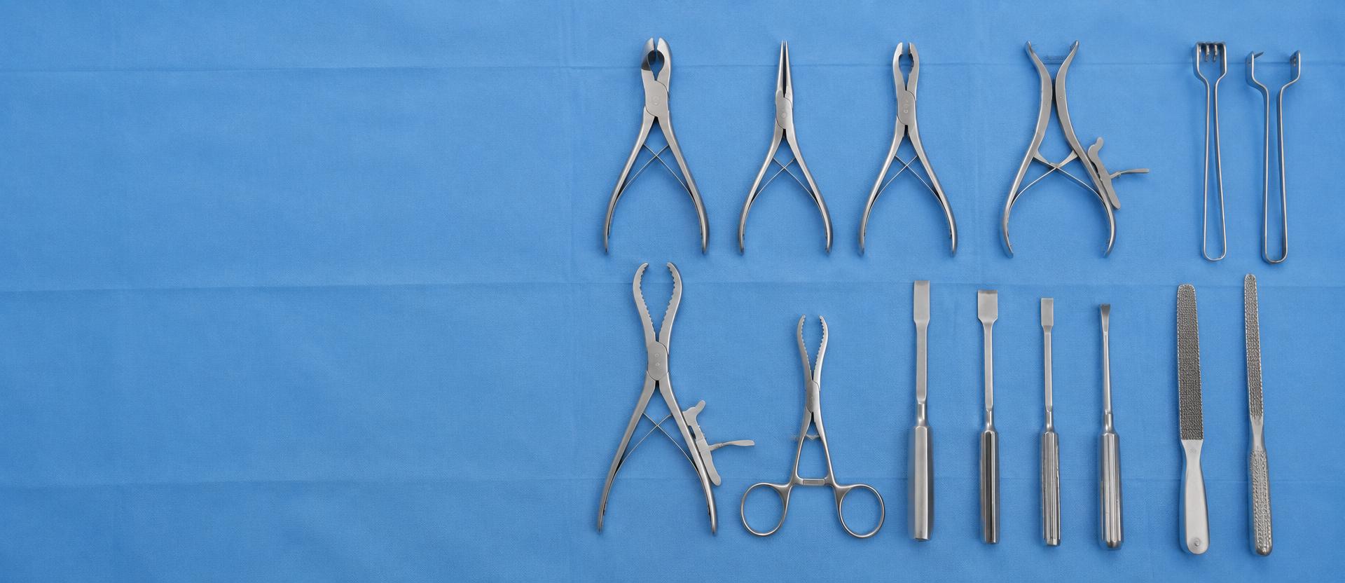 Reusable stainless steel orthopedic hand instruments arranged on a blue surgical drape